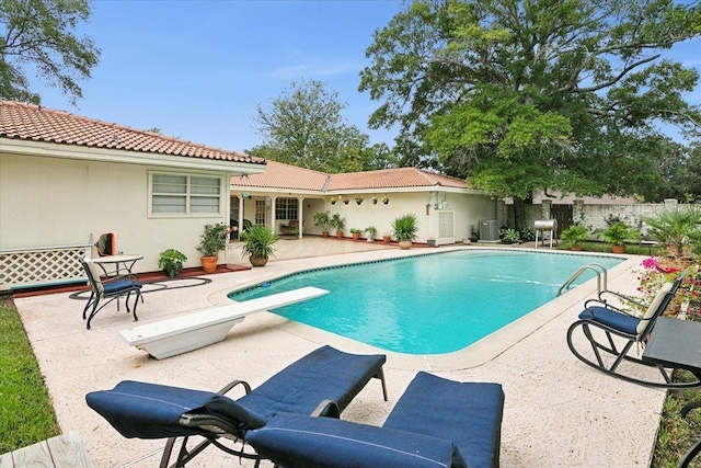 view of pool featuring central AC unit, a diving board, and a patio