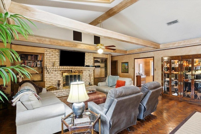 living room featuring beam ceiling, built in shelves, ceiling fan, a brick fireplace, and dark parquet floors