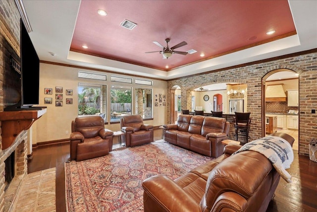 970 Hibiscus Cir, Beaumont, TX 77706 - living area featuring a tray ceiling, arched walkways, light wood-type flooring, a ceiling fan, and a fireplace