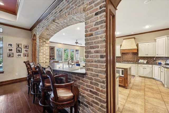 970 Hibiscus Cir, Beaumont, TX 77706 - kitchen featuring ornamental molding, a ceiling fan, an island with sink, a breakfast bar area, and decorative backsplash