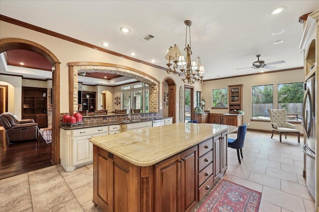 970 Hibiscus Cir, Beaumont, TX 77706 - kitchen featuring arched walkways, ornamental molding, a ceiling fan, light stone counters, and a center island