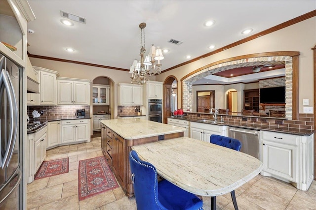 970 Hibiscus Cir, Beaumont, TX 77706 - kitchen with crown molding, arched walkways, backsplash, a chandelier, and dark stone counters