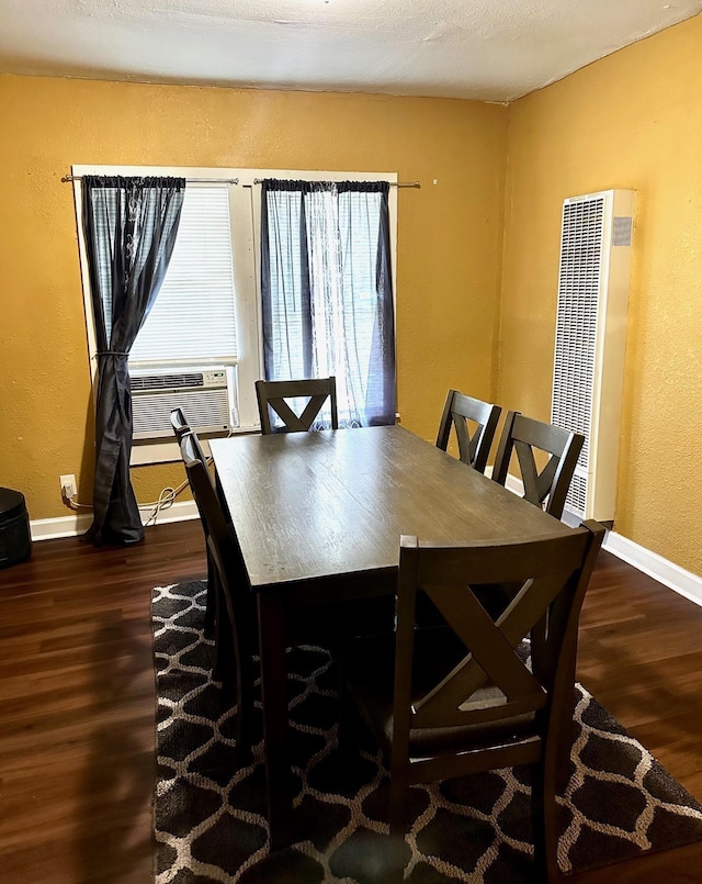 dining space featuring a heating unit, baseboards, wood finished floors, and a textured wall