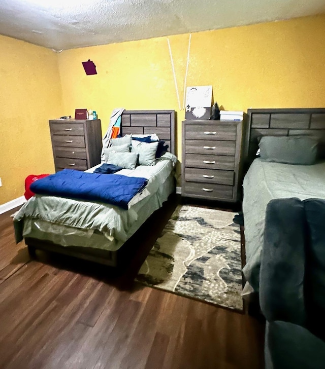 bedroom with wood finished floors, baseboards, and a textured ceiling