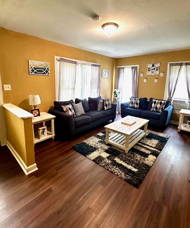 living area featuring a textured ceiling, a textured wall, and dark wood-style flooring