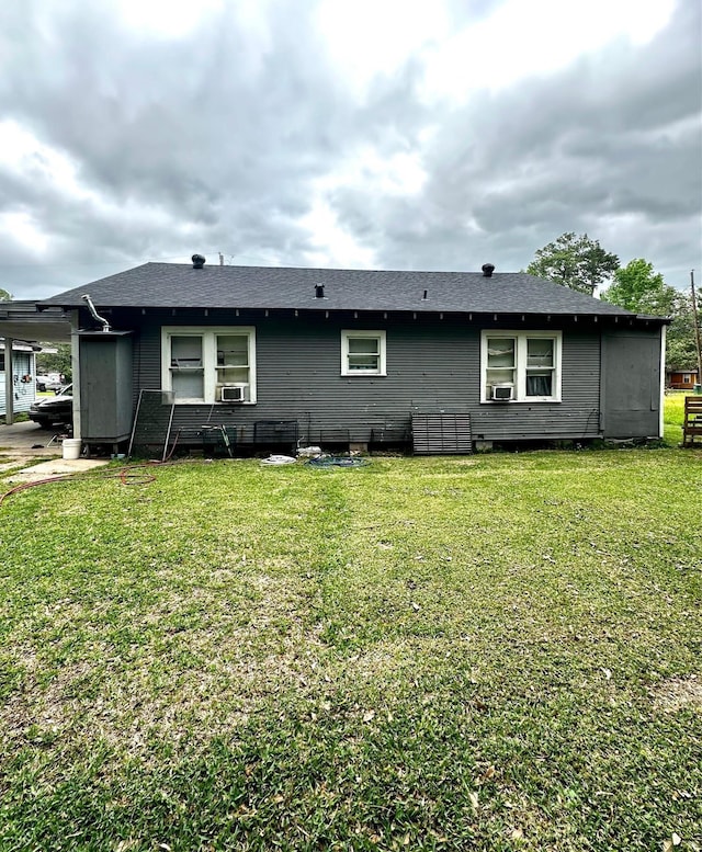 back of property featuring a lawn, cooling unit, and a shingled roof