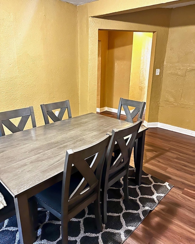 dining space with wood finished floors, baseboards, and a textured wall