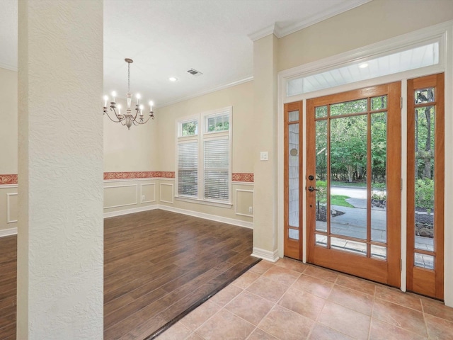 9670 Manion Ct, Beaumont, TX 77706 - tiled foyer featuring a decorative wall, crown molding, wainscoting, an inviting chandelier, and visible vents