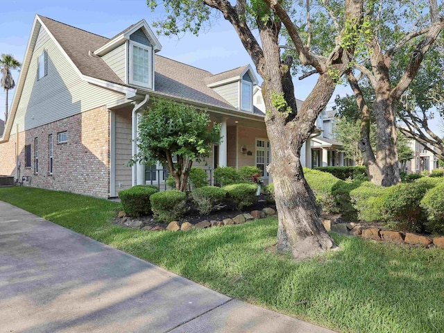 9670 Manion Ct, Beaumont, TX 77706 - cape cod home featuring a shingled roof, a front lawn, brick siding, and cooling unit