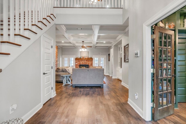 entryway featuring coffered ceiling, a brick fireplace, ceiling fan, beamed ceiling, and wood-type flooring