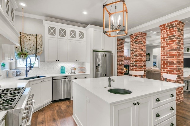 kitchen featuring high end appliances, a kitchen island with sink, white cabinets, sink, and decorative backsplash