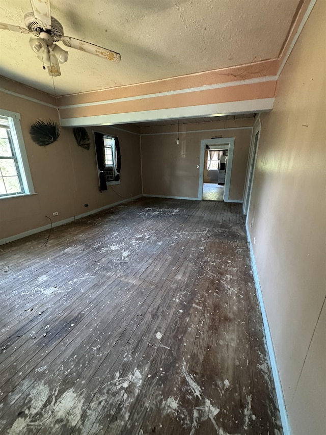 empty room with a textured ceiling, ceiling fan, and dark hardwood / wood-style floors