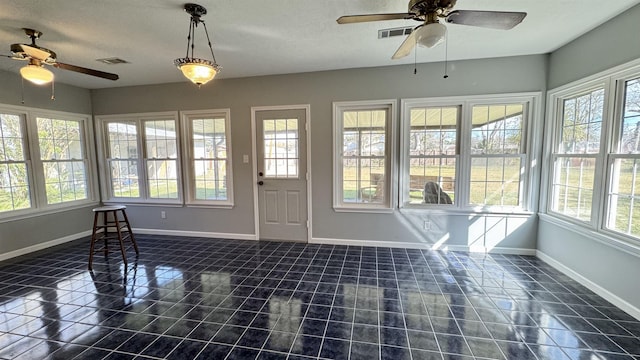 unfurnished sunroom featuring ceiling fan and a healthy amount of sunlight