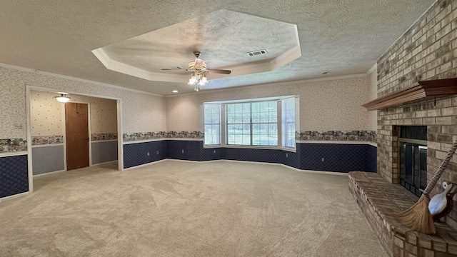 unfurnished living room featuring a fireplace, a raised ceiling, ceiling fan, and carpet flooring