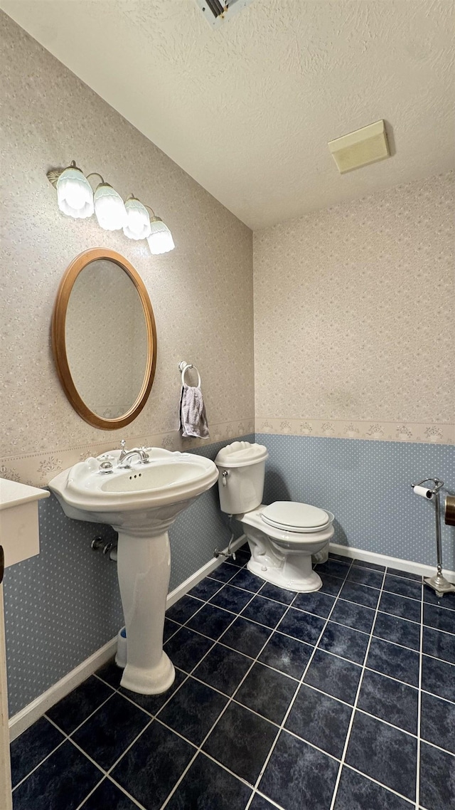 bathroom with toilet, tile patterned floors, and a textured ceiling