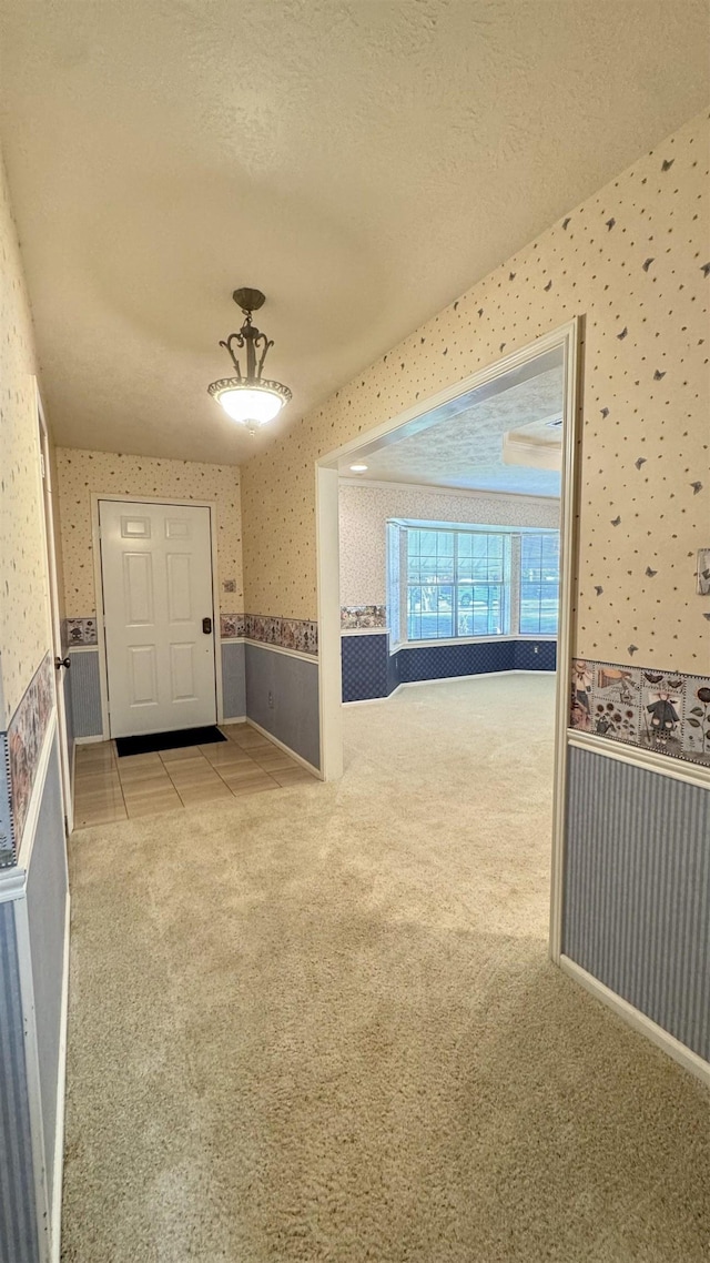 hallway with a textured ceiling and light colored carpet