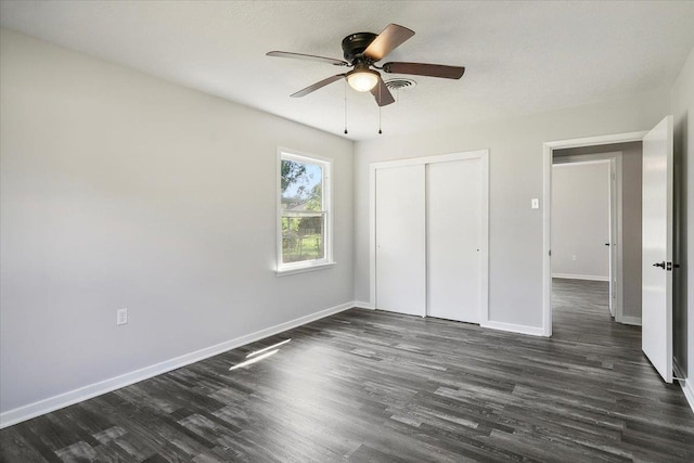 unfurnished bedroom with ceiling fan, dark wood-type flooring, and a closet