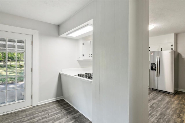 kitchen with stainless steel fridge, white cabinets, dark wood-type flooring, and a textured ceiling