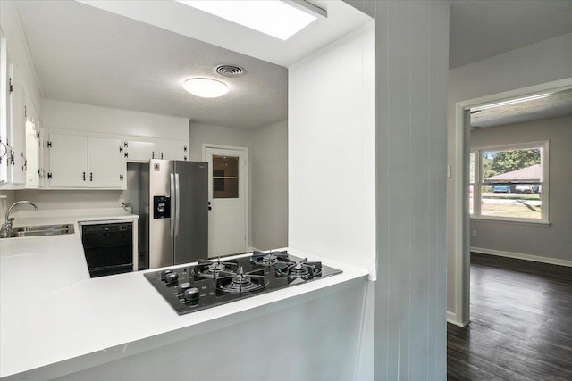 kitchen featuring dark wood-type flooring, black appliances, white cabinets, sink, and kitchen peninsula