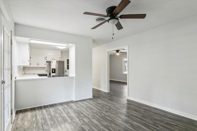 unfurnished living room featuring ceiling fan, sink, and dark wood-type flooring