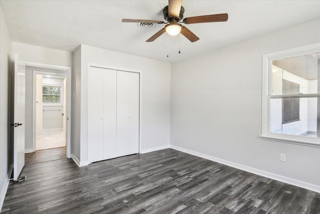 unfurnished bedroom with ceiling fan, dark wood-type flooring, and a closet