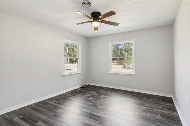 spare room featuring a healthy amount of sunlight, dark hardwood / wood-style flooring, and a textured ceiling