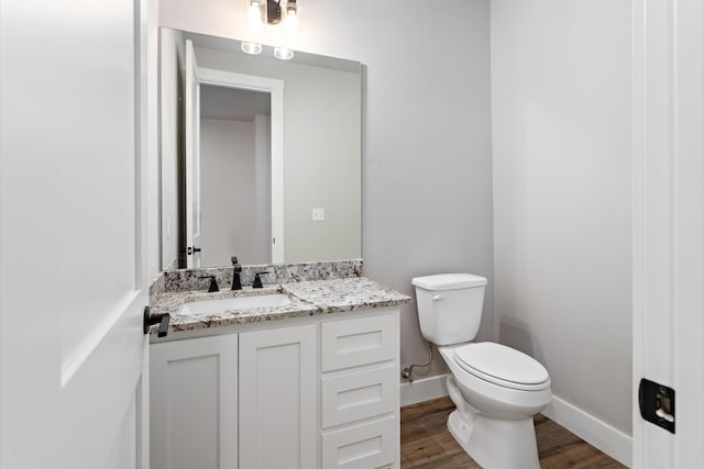 bathroom with toilet, vanity, and hardwood / wood-style flooring