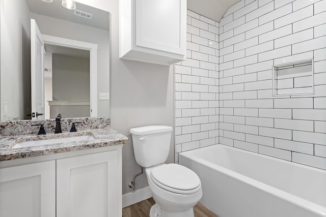 full bathroom with tiled shower / bath, hardwood / wood-style flooring, vanity, and toilet