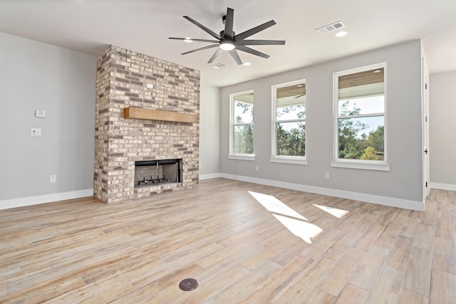 unfurnished living room featuring ceiling fan, light wood-type flooring, and a fireplace