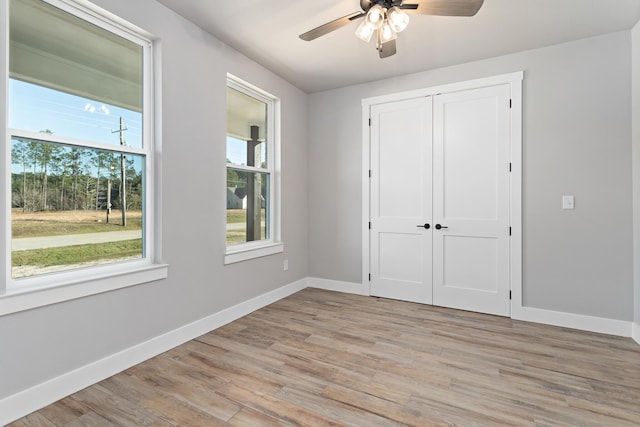 unfurnished bedroom featuring ceiling fan, light wood-type flooring, and a closet