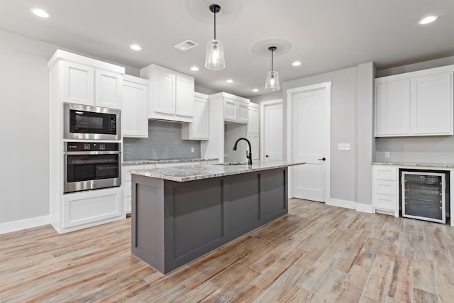 kitchen featuring wine cooler, white cabinetry, oven, and built in microwave