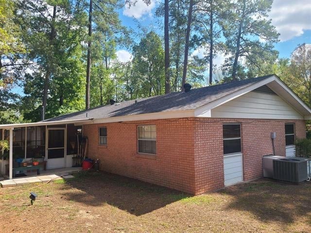 rear view of property with central AC, a lawn, and a sunroom