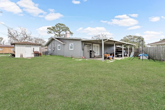 back of house featuring a fenced backyard, a storage shed, an outdoor structure, a lawn, and a chimney