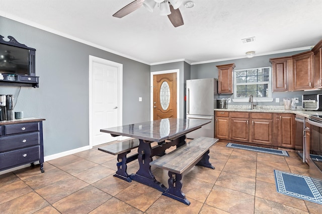 kitchen with visible vents, baseboards, freestanding refrigerator, and crown molding