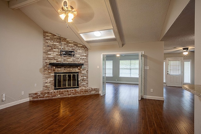 unfurnished living room with ceiling fan, plenty of natural light, lofted ceiling with beams, and a brick fireplace