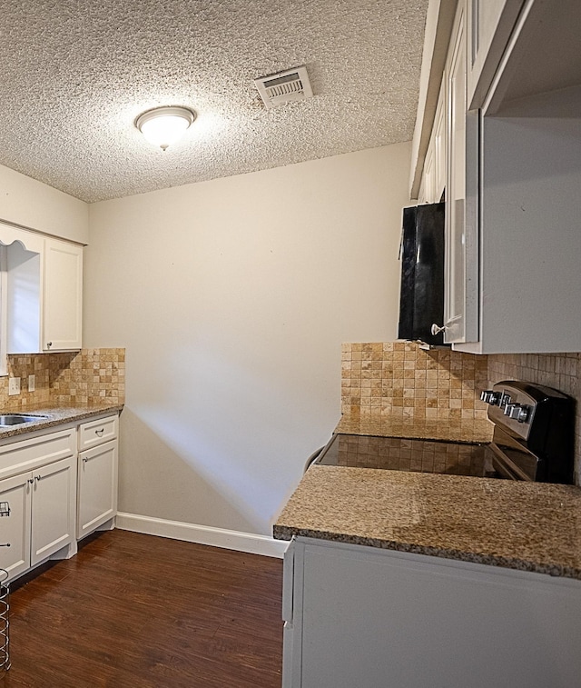 kitchen with white cabinets, decorative backsplash, dark hardwood / wood-style flooring, and stainless steel range with electric stovetop