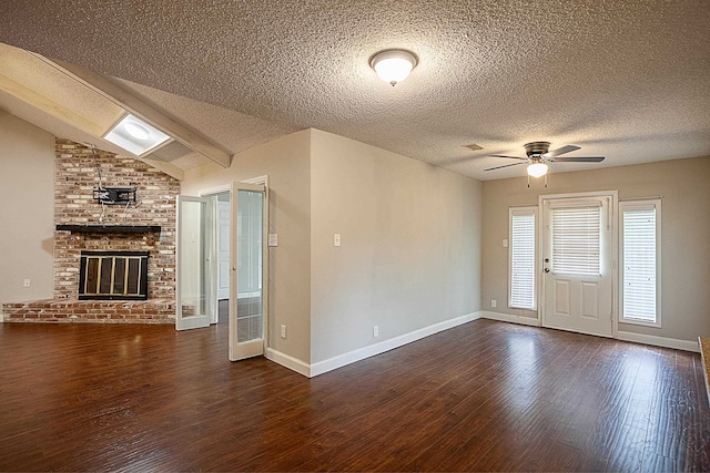 unfurnished living room featuring vaulted ceiling with beams, ceiling fan, dark hardwood / wood-style floors, and a brick fireplace