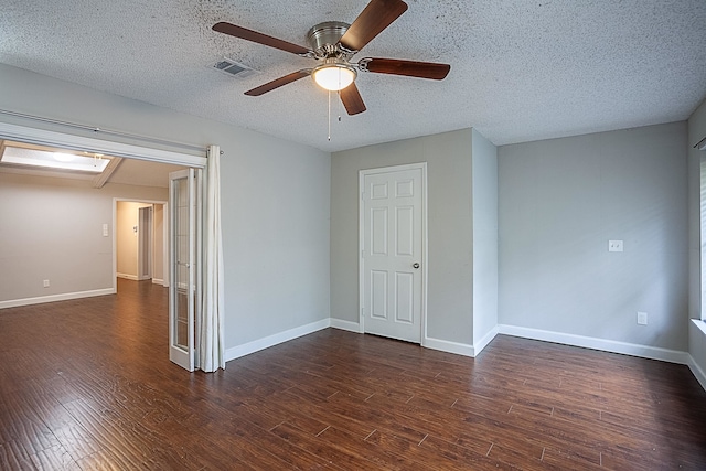 spare room with a textured ceiling, ceiling fan, and dark wood-type flooring