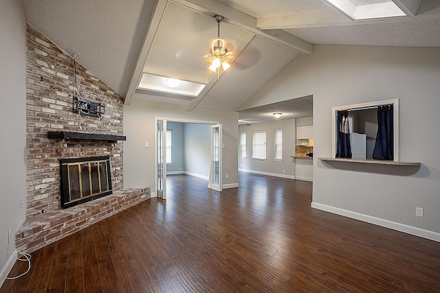 unfurnished living room with a brick fireplace, vaulted ceiling with beams, ceiling fan, a textured ceiling, and dark hardwood / wood-style flooring