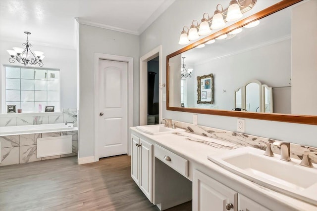 bathroom with vanity, crown molding, hardwood / wood-style flooring, tiled tub, and a chandelier