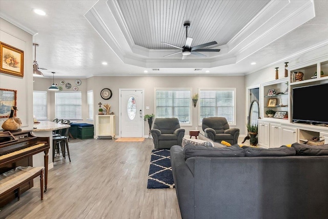 living room with ceiling fan, wooden ceiling, ornamental molding, a tray ceiling, and light wood-type flooring