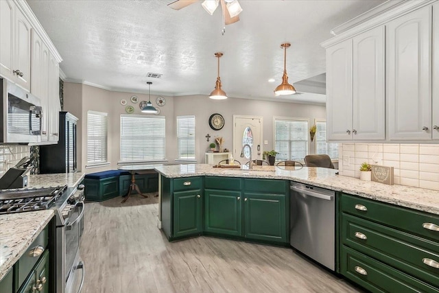 kitchen with decorative backsplash, white cabinetry, stainless steel appliances, and decorative light fixtures