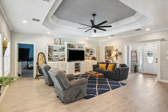 living room featuring a tray ceiling, crown molding, plenty of natural light, and light hardwood / wood-style floors