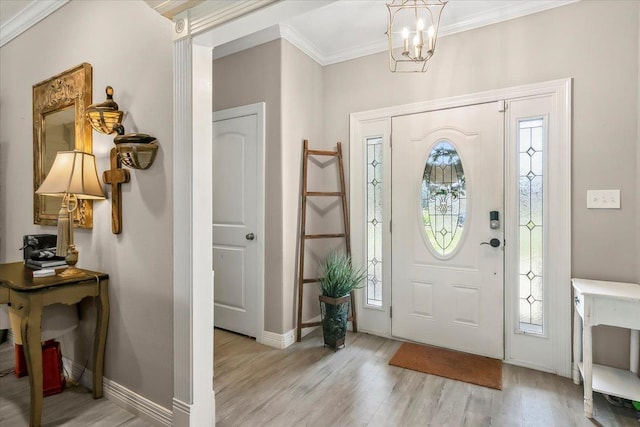 foyer entrance with a notable chandelier, a healthy amount of sunlight, ornamental molding, and light hardwood / wood-style flooring