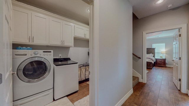 108 Colonial Estates Dr, Bridge City, TX 77611 - laundry room featuring cabinet space, wood finished floors, baseboards, and independent washer and dryer