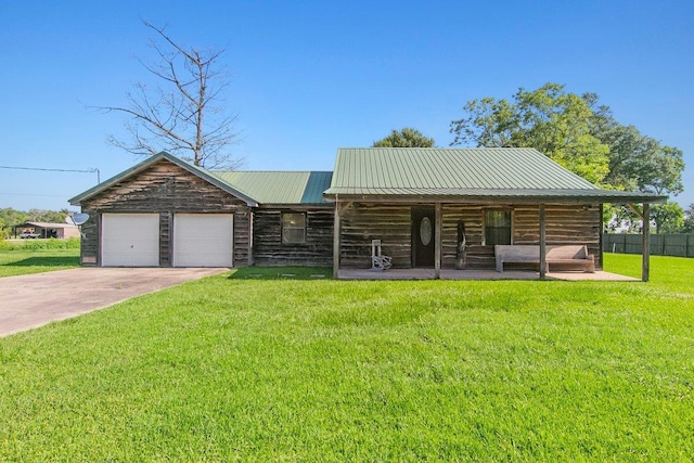 cabin with covered porch, a garage, and a front lawn