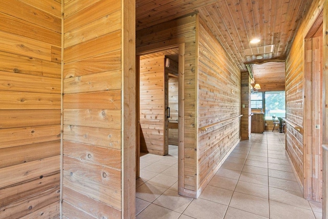 hall featuring tile patterned floors, wood walls, and wood ceiling