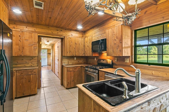 kitchen featuring wood walls, wooden ceiling, black appliances, sink, and light tile patterned flooring