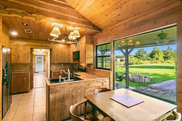 kitchen featuring sink, black appliances, light tile patterned floors, wooden ceiling, and wood walls