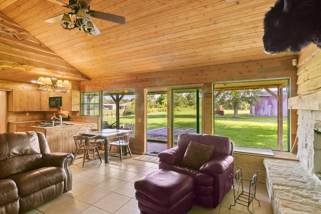 tiled living room with ceiling fan with notable chandelier, a wealth of natural light, sink, and wooden walls